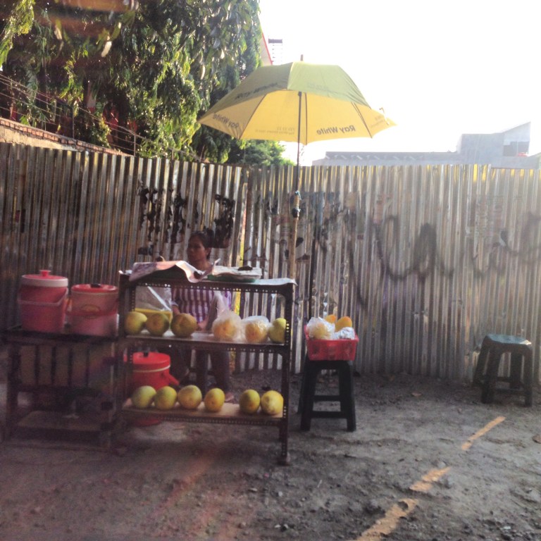 A woman sells timun suri (lemon cucumber) prior to breaking fast during Ramadan, against a silver backdrop.